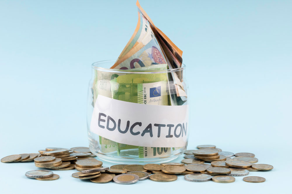 Ein Glas mit Geldscheinen und Münzen, beschriftet mit 'EDUCATION', symbolisiert Spenden im Bildungsbereich.
