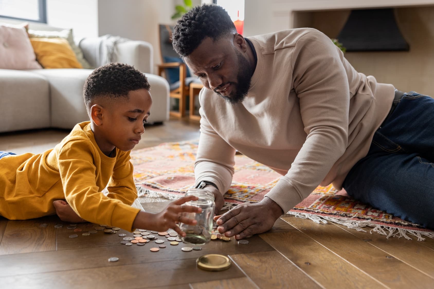 father and son counting coins on the floor from a glass jar