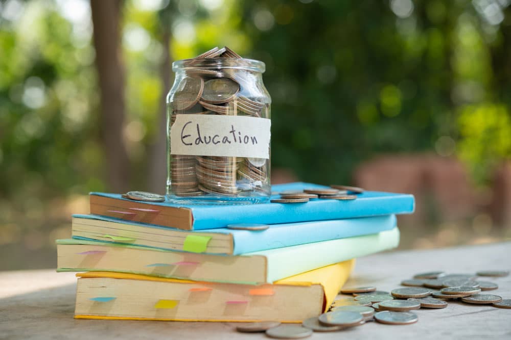 Donation for education: A jar of coins on books symbolizing CSR strategies.