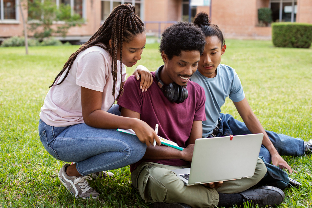 Students collaborating on a laptop outdoors, showcasing digital literacy and education empowerment.