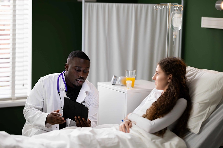 Afrikanisches Gesundheitspersonal verwendet ein Tablet, um einem jungen Patienten eine Krankheit zu erklären.