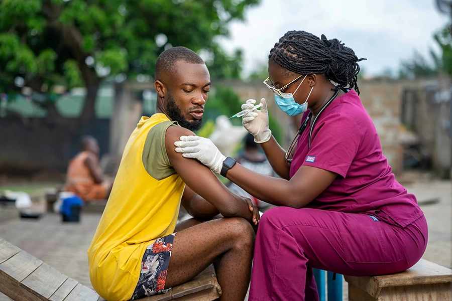 Afrikanisches Gesundheitspersonal behandelt einen jungen Patienten im Freien und zeigt dabei persönliche Betreuung
