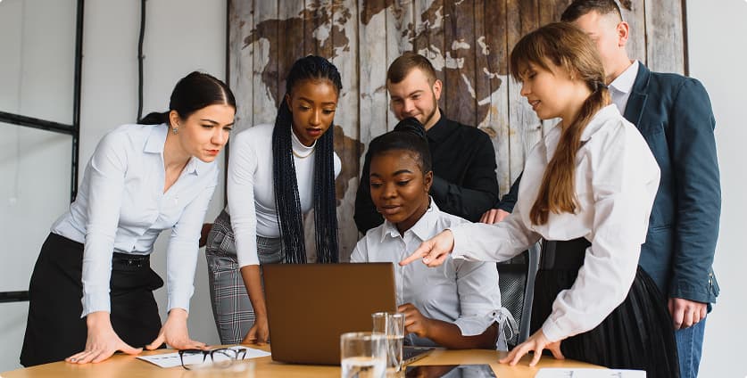 Team, das bei einer Besprechung im modernen Büro gemeinsam an einem Laptop arbeitet.